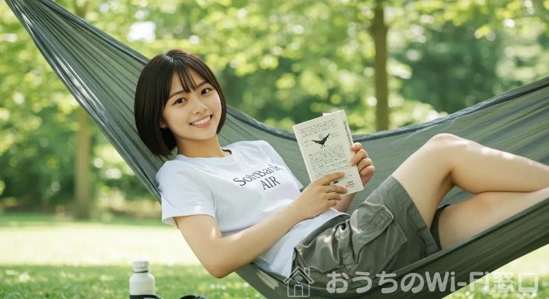 SoftBank Airのロゴ付きTシャツを着て、ハンモックで読書している若い日本人女性